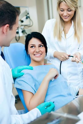 Oral surgeon and dental assistant working with a patient